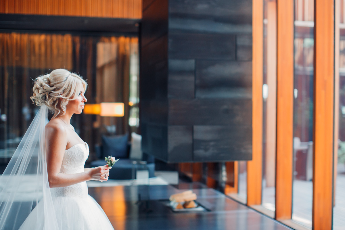 A blond bride standing in the room and looking out of the window